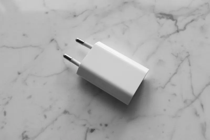 A white adapter placed on a smooth marble surface, showcasing minimalistic design